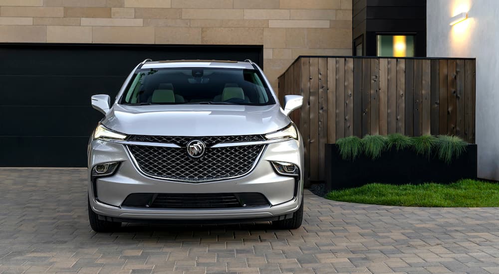 A silver 2022 Buick Enclave is shown from the front parked in front of a modern house.