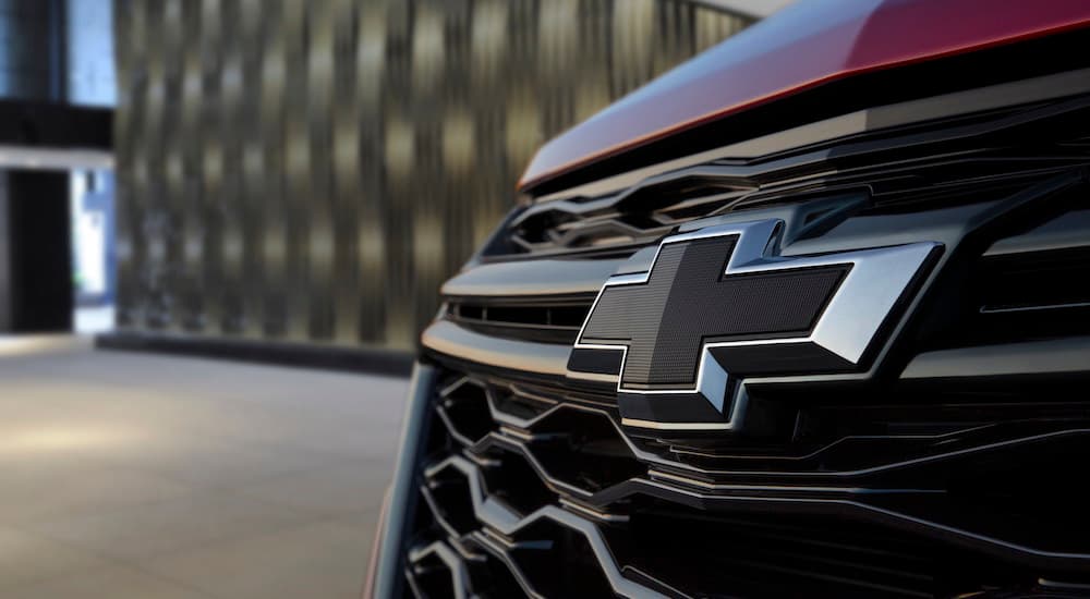 A close up of the front grille of a red 2022 Chevy Equinox shows the Chevy bowtie.