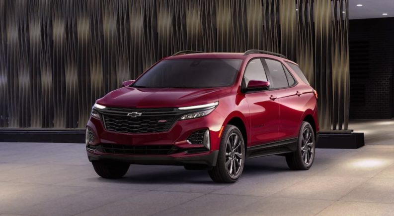 A red 2022 Chevy Equinox is shown from the front parked in a modern gallery.