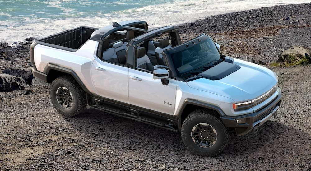 A silver 2022 GMC Hummer EV Pickup is parked in front of the beach.