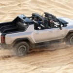 A silver 2022 GMC Hummer EV pickup is off-roading through the desert.