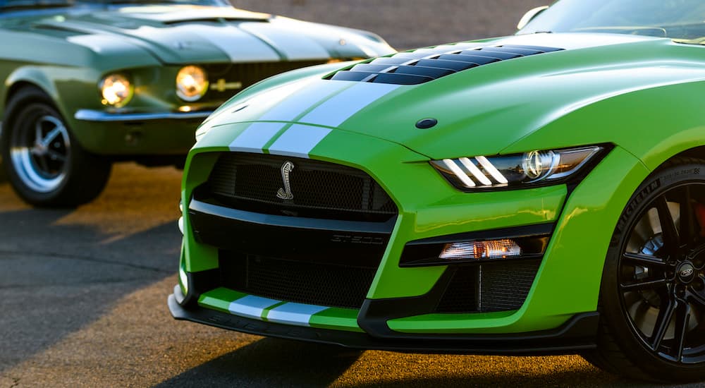 A green 2021 Ford Mustang GT500 is parked next to a 1967 Mustang.