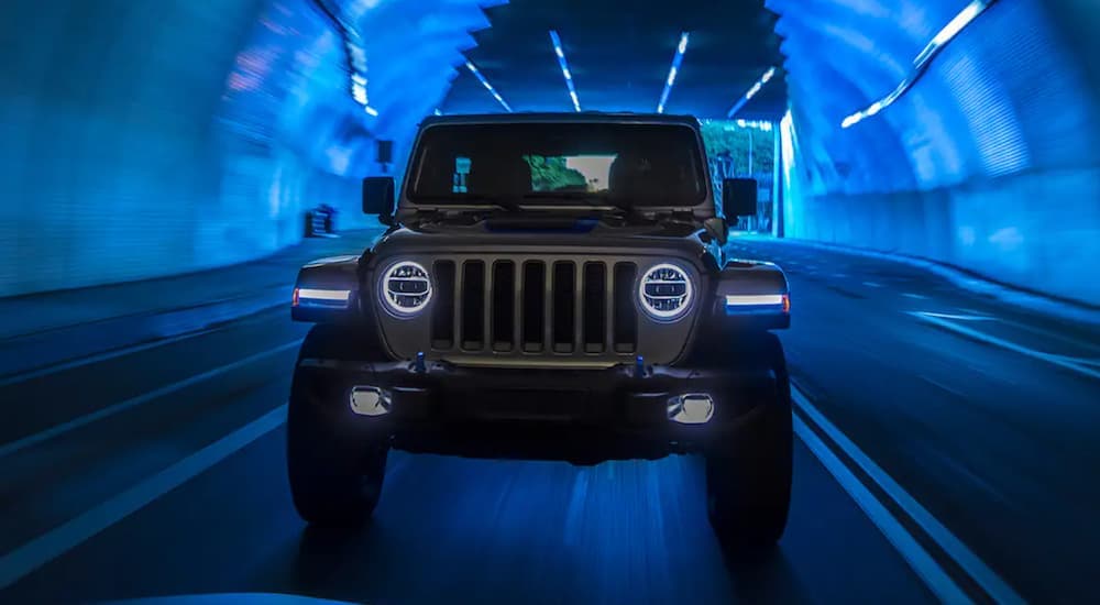 A grey 2021 Jeep Wrangler 4xe is shown from the front driving through a tunnel.