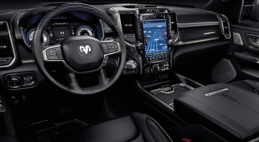 The black interior of a 2021 Ram 1500 shows the steering wheel and infotainment screen.
