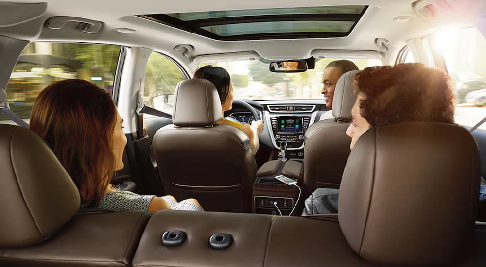 The tan interior of a 2021 Nissan Murano shows a family of four sitting inside.