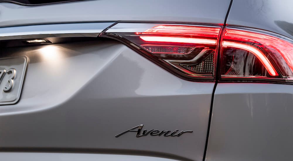 A close up shows the passanger taillight and badge on a silver 2022 Buick Enclave Avenir.