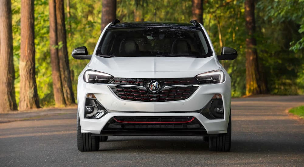 A white 2022 Buick Encore GX is shown from the front parked on a road in the forest.
