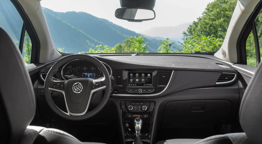 The black interior of a 2022 Buick Encore shows the steering wheel and infotainment screen.