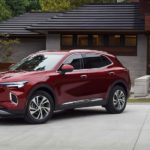 A red 2022 Buick Envision is shown from the side parked in front of a modern house.