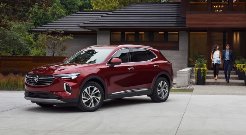 A red 2022 Buick Envision is shown from the side parked in front of a modern house.