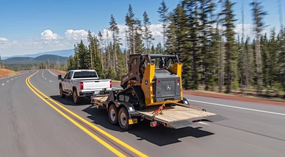 A 2022 Chevy Silverado 2500HD is shown towing a trailer on a highway.
