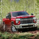 A 2022 Chevy Silverado 2500 HD is shown from the front driving on a forest trail
