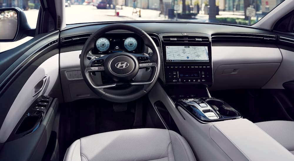 The black and silver interior, steering wheel, and infotainment screen are shown in a 2022 Hyundai Tuscon.