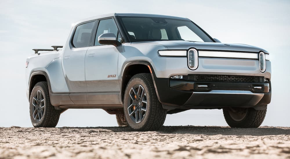 A silver 2022 Rivian R1T is shown parked on sand.