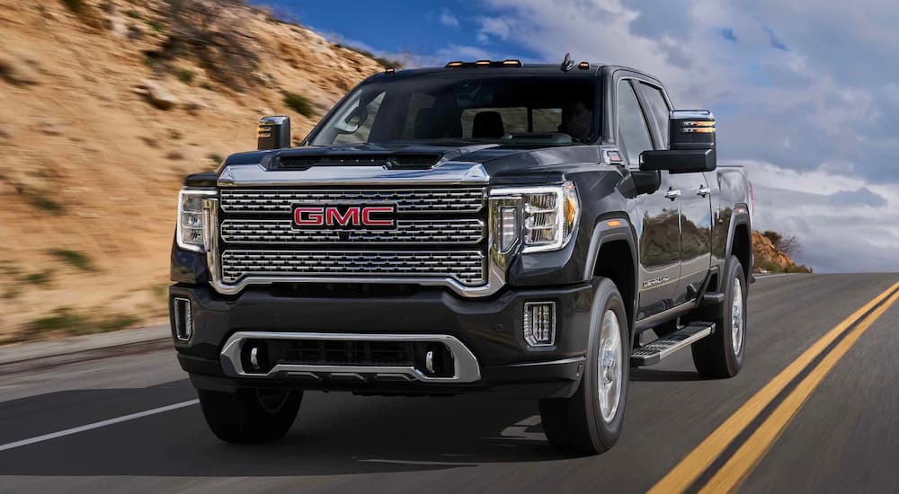 A black 2022 GMC Sierra 2500HD is shown from the front as it drives down a highway during a 2022 Ford F-250 vs 2022 GMC Sierra 2500HD comparison.
