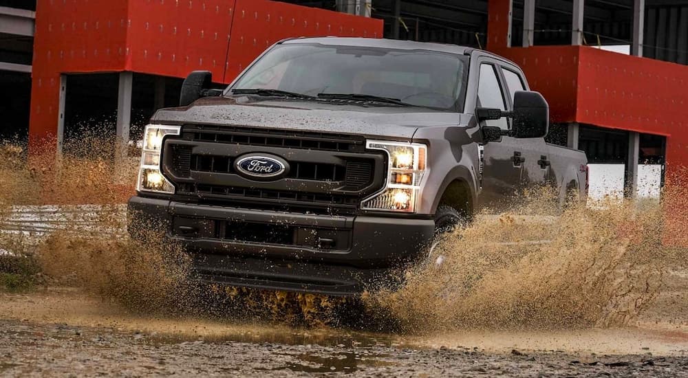 A brown Ford F-350 XL is shown driving through a muddy puddle during a 2022 Ford F-350 vs 2022 GMC Sierra 3500 HD comparison.