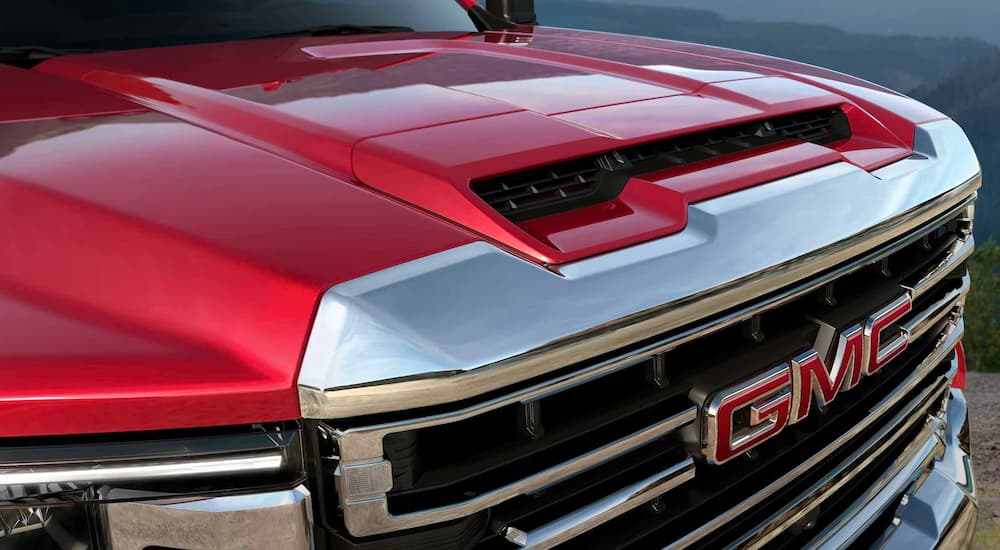 A close up of a red 2022 GMC Sierra 2500HD SLT shows the hood and grille.