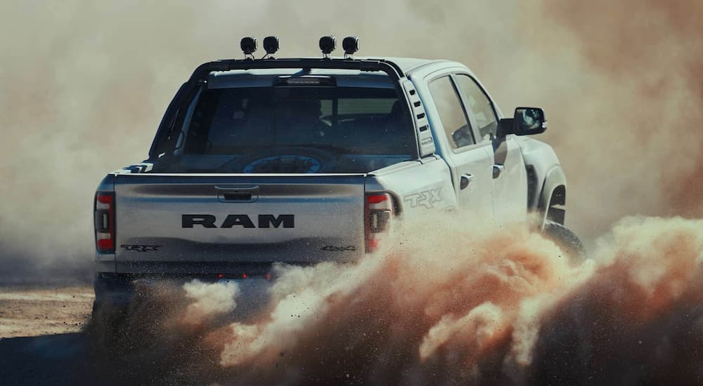 A white 2022 Ram 1500 is shown from the rear off-roading in a desert.