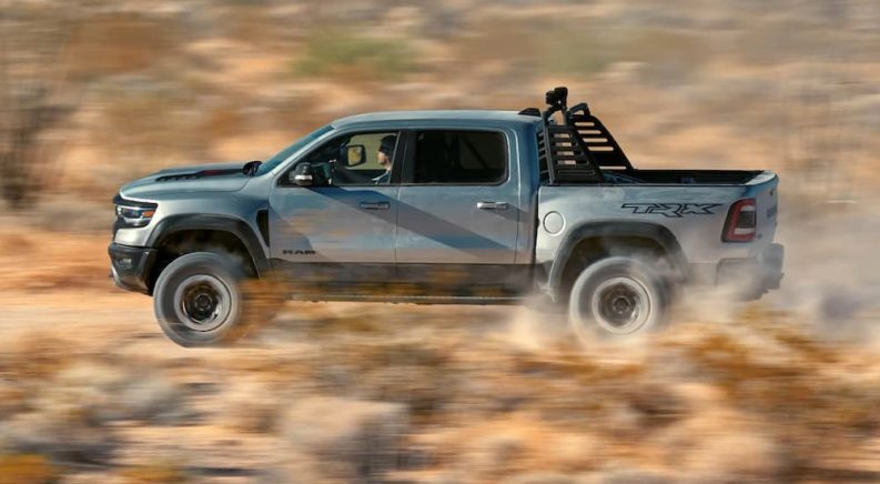 A grey 2022 Ram 1500 TRX is shown from the side off-roading through the desert.