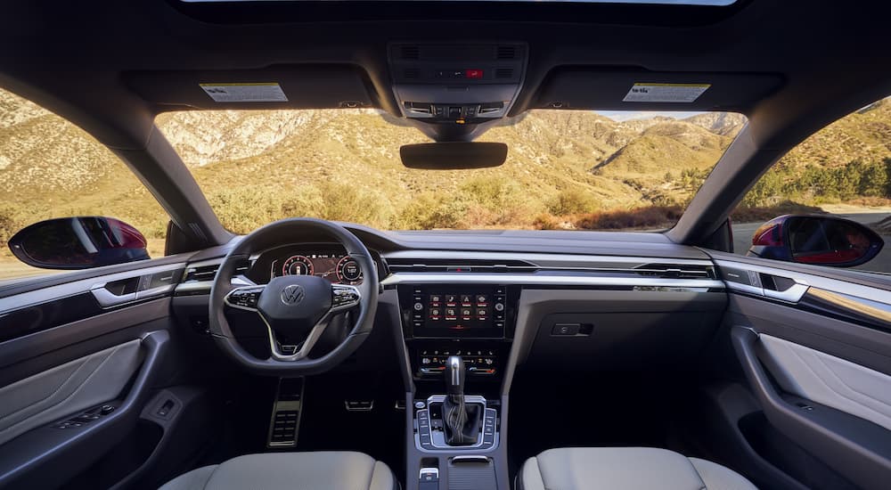 The black and silver interior of a 2022 Volkswagen Arteon shows the steering wheel and center console.