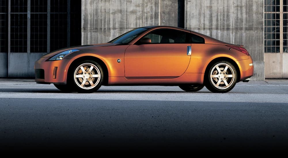 An orange 2005 Nissan Z is shown from the side parked on a city street.