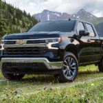 A black 2022 Chevy Silverado 1500 is shown parked in a field near mountains.