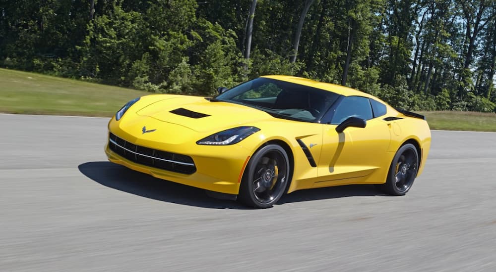 A yellow 2014 Chevy Corvette is shown driving down a road.