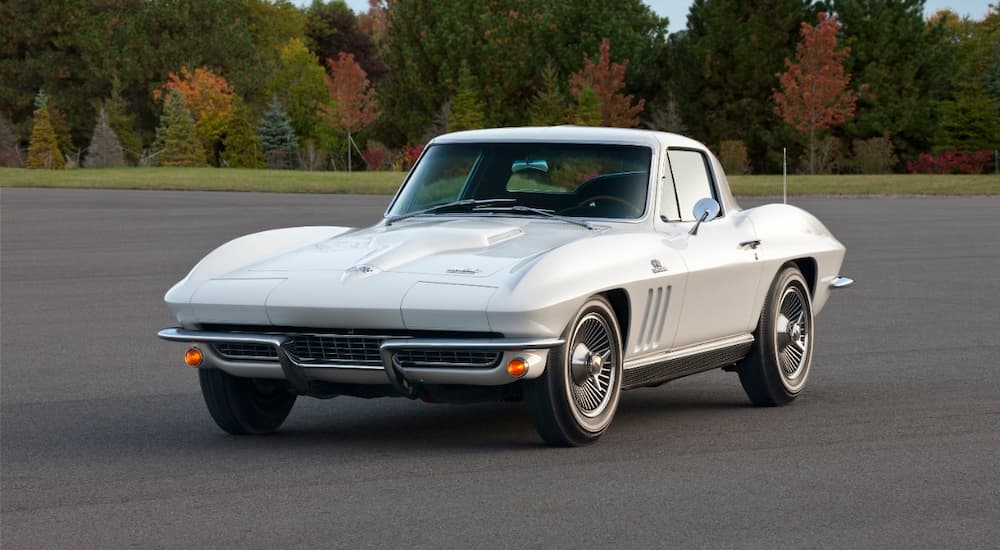 A silver 1966 Chevy Corvette is shown parked in an empty parking lot.