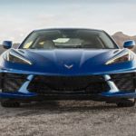 A blue 2021 Chevy Corvette Stingray is shown from the front while parked in a desert.
