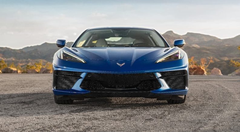 A blue 2021 Chevy Corvette Stingray is shown from the front while parked in a desert.