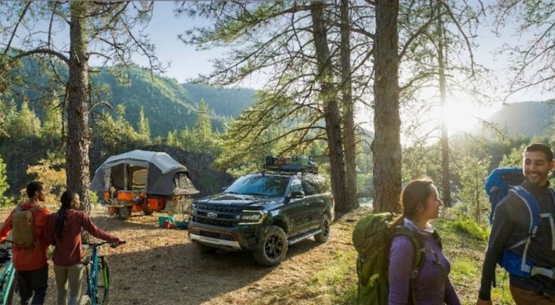 A 2022 Ford Expedition Timberline is shown parked next to a campsite with hikers passing by.