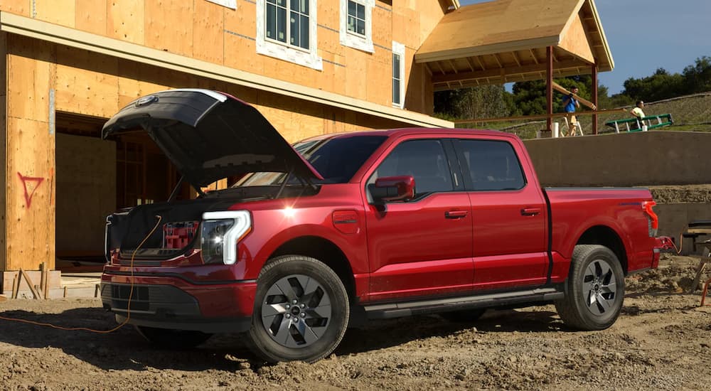 A red 2022 Ford F-150 Lightning is shown parked on a construction site.
