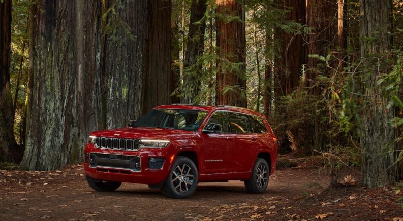 A red 2022 Jeep Grand Cherokee L Overland is shown parked on a forest trail.