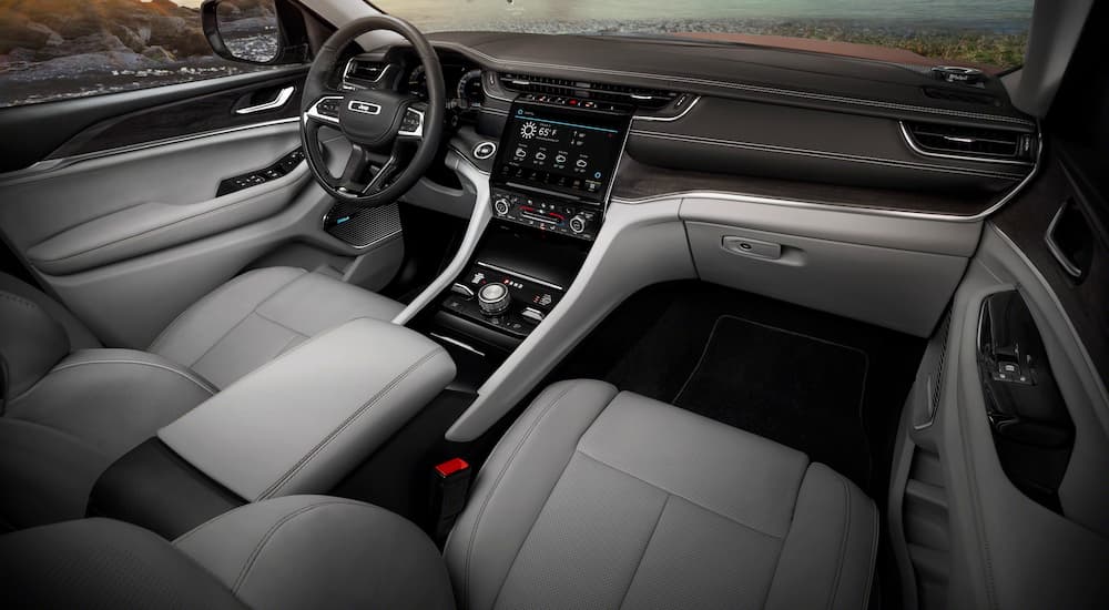 The grey and black interior of a 2022 Grand Cherokee L shows the steering wheel and infotainment screen.