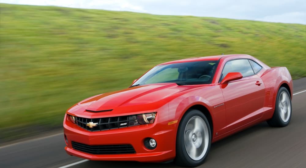 A red 2010 Chevy Camaro is shown driving on a road.