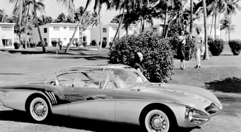 A 1956 Buick Centurion is driving down a street shown in black and white.