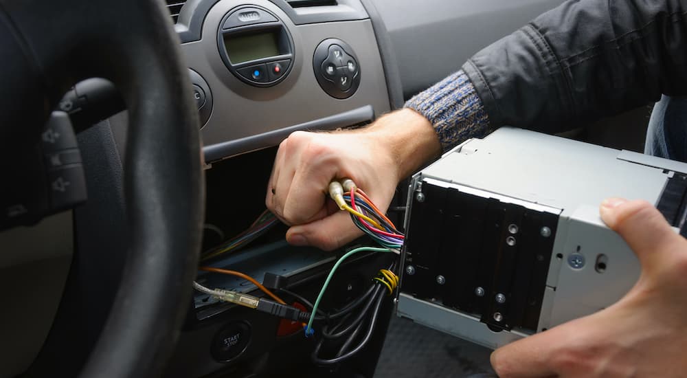 A close up shows a head unit being removed from a car purchased at a used car dealership.