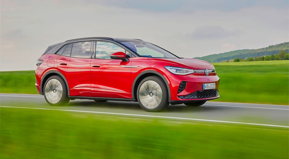A red 2021 Volkswagen ID.4 GTX is shown driving along a highway after leaving Volkswagen electric car dealer.