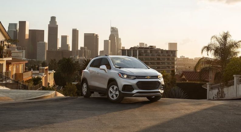 A white 2021 Chevy Trax is shown parked on a hilltop overlooking a city.