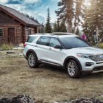 A white 2021 Ford Explorer is shown parked near a log cabin.