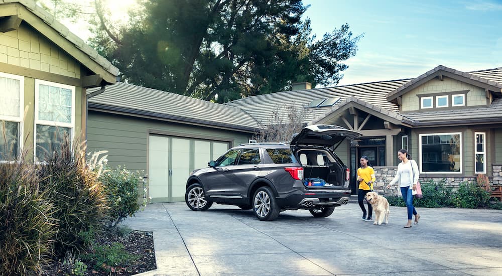 A family is shown standing near a grey 2021 Ford Explorer parked in a driveway.