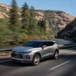 A silver 2022 Chevy Blazer Premium is shown driving on a highway through the mountains.