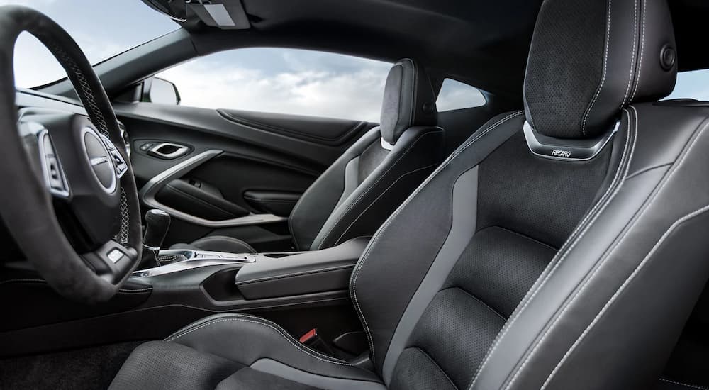 The black and grey interior of a 2022 Chevy Camaro ZL1 1LE shows the drivers seat and steering wheel.
