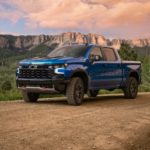 A blue 2022 Chevy Silverado 1500 ZR2 is shown parked on a dirt road during a sunset.