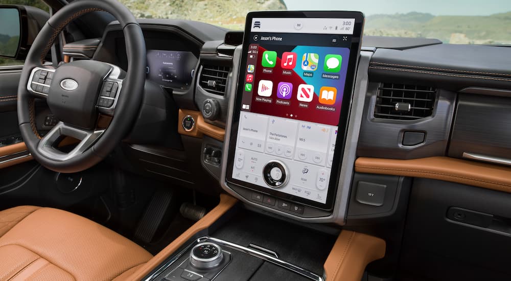 The tan and black interior of a 2022 Ford Expedition Platinum Edition shows the infotainment screen and steering wheel.