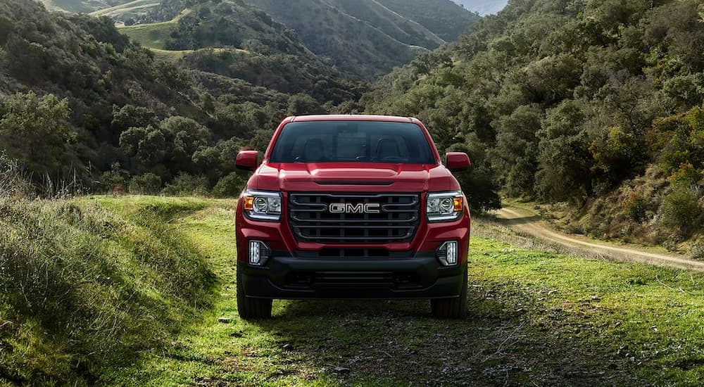A red 2022 GMC Canyon is shown from the front parked on a grassy road.