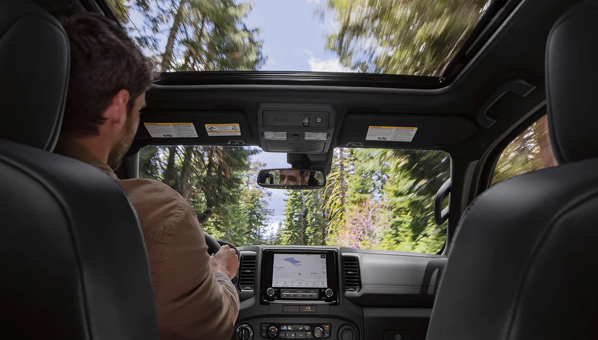 A man is shown driving a 2022 Nissan Frontier during a 2022 Nissan Frontier vs 2022 Chevy Colorado comparison.