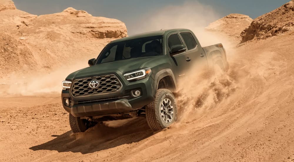 A green 2022 Toyota Tacoma TRD is shown driving in the desert during a 2022 Nissan Frontier vs 2022 Toyota Tacoma comparison.
