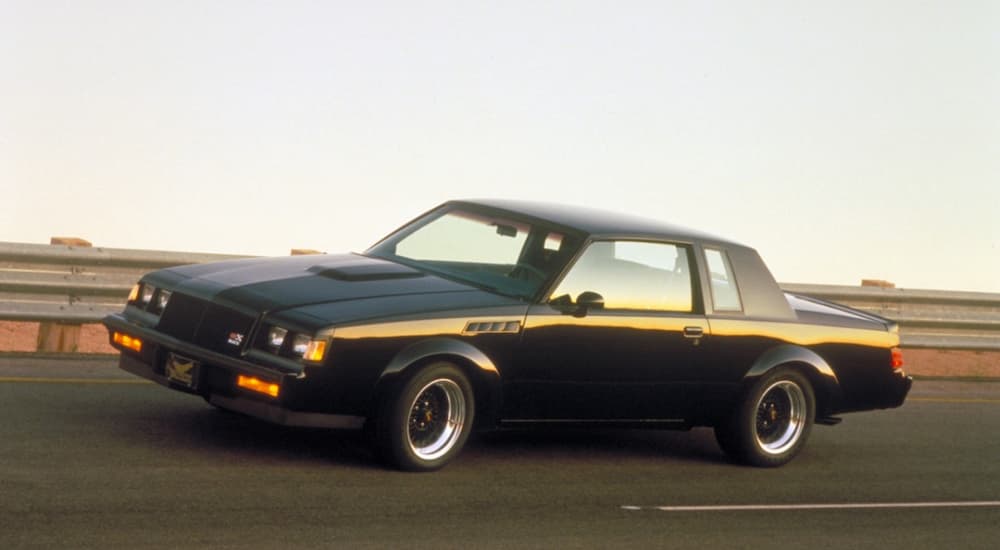 A black 1987 Buick Regal GNX is shown driving on a track.