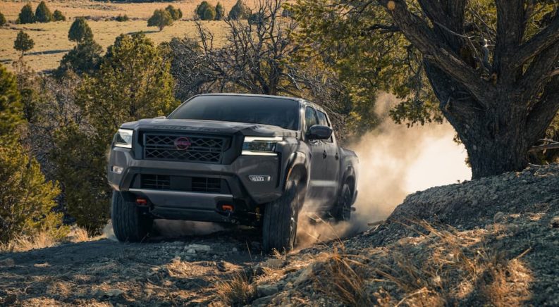 A grey 2022 Nissan Frontier is shown driving up a steep rocky hill during a 2022 Nissan Frontier vs 2022 GMC Canyon comparison.